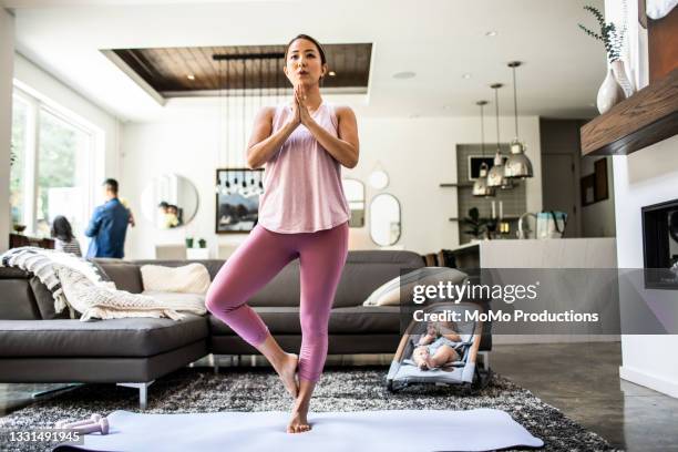 mother doing yoga at home surrounded by children - op een been staan stockfoto's en -beelden