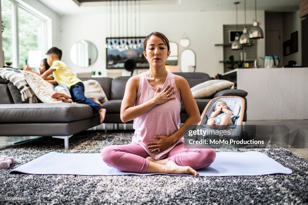 Mother doing yoga at home surrounded by children