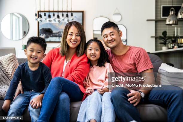 portrait of family at home on couch - korean ethnicity stock-fotos und bilder