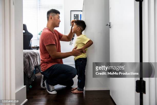 father measuring son's height on wall - height ストックフォトと画像