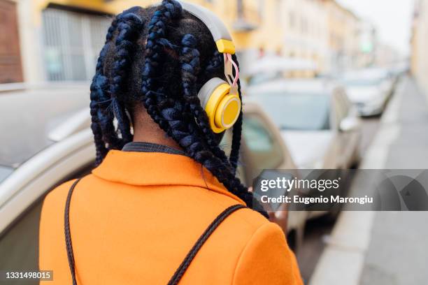 italy, milan, rear view of woman with braided hair and headphones - frau zopf hinten stock-fotos und bilder