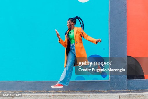 Italy, Milan, Woman with braids jumping against blue wall Italy, Milan, Woman with braids jumping against blue wall