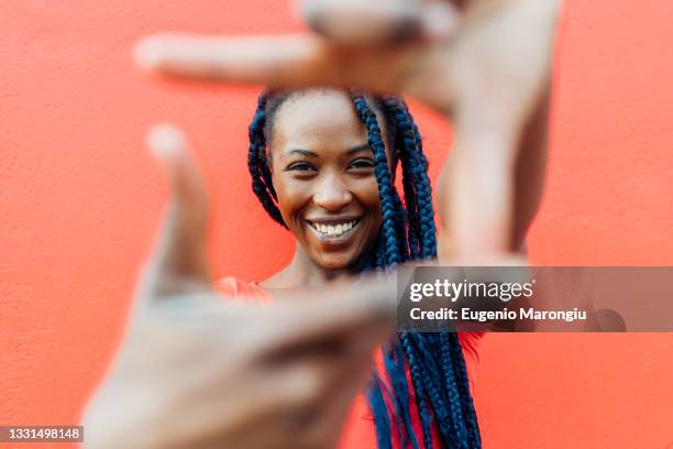 italy, milan, portrait of young woman with braids making finger frame - focus noir photos et images de collection