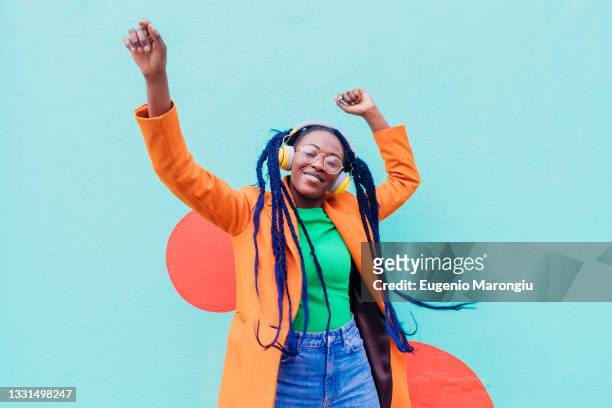 italy, milan, stylish woman with headphones dancing against wall - fashion orange colour stock pictures, royalty-free photos & images