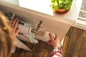 Woman adjusting the temperature on valve of a radiator at home, modern interior background photo