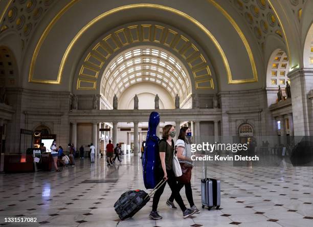 People wear masks as they walk through Union Station on July 30, 2021 in Washington, DC. DC Mayor Muriel Bowser restored a COVID-19 indoor mask...