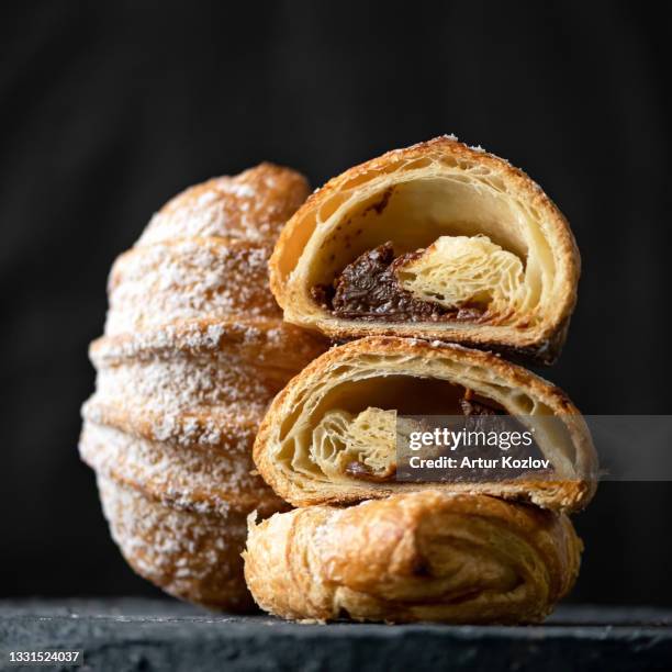 croissant stuffed with chocolate. halves of puff pastry with chocolate filling on black background. side view. close-up shot - brioche stock pictures, royalty-free photos & images