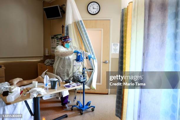 Certified Nursing Assistant Paulette Santillan departs after checking a COVID-19 patient's vital signs in the improvised COVID-19 unit at Providence...