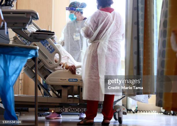 Registered nurse Elle Lauron ( and another caregiver care for a COVID-19 patient in the improvised COVID-19 unit at Providence Holy Cross Medical...