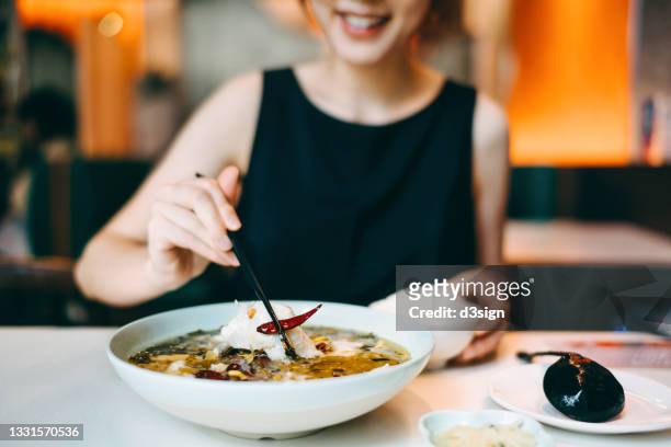 smiling young asian woman enjoying traditional chinese szechuan cuisine, boiled fish with pickled cabbage in a restaurant. asian food and cuisine. eating out lifestyle - szechuan cuisine ストックフォトと画像