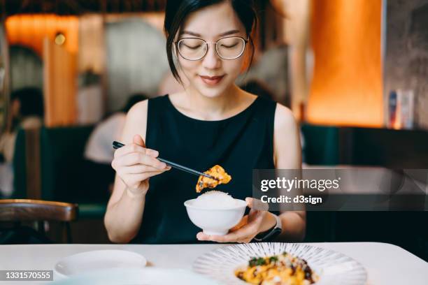 smiling young asian woman enjoying traditional chinese szechuan cuisine, spicy chicken in chilli oil in a restaurant. asian food and cuisine. eating out lifestyle - szechuan cuisine ストックフォトと画像