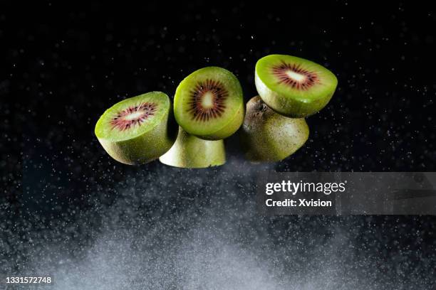 kiwi fruit dancing in mid air with flour captured with high speed sync. - flying kiwi stock pictures, royalty-free photos & images