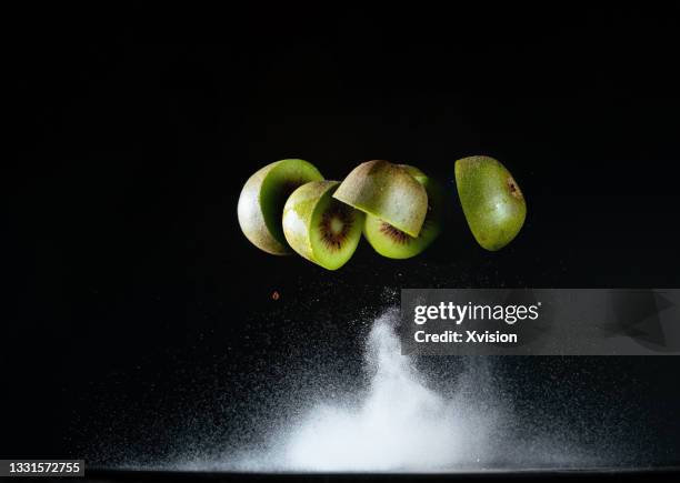 kiwi fruit dancing in mid air with flour captured with high speed sync. - flying kiwi stock pictures, royalty-free photos & images