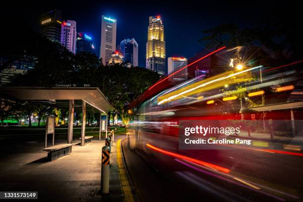 streaks of light trails with glowing city skyscrapers in the background. - singapore stock pictures, royalty-free photos & images