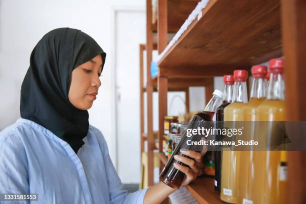 indonesian muslim woman buying honey in an organic store - manuka honey stock pictures, royalty-free photos & images