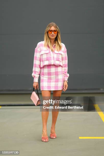 Ioana Chisiu wears orange sunglasses, a white and pink checkered print pattern shirt, a matching white and pink checkered print pattern short skirt,...