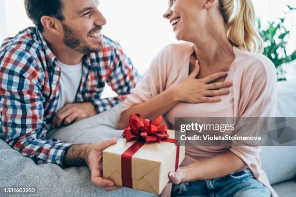 cheerful young woman receiving a gift from her boyfriend. - passas stock pictures, royalty-free photos & images