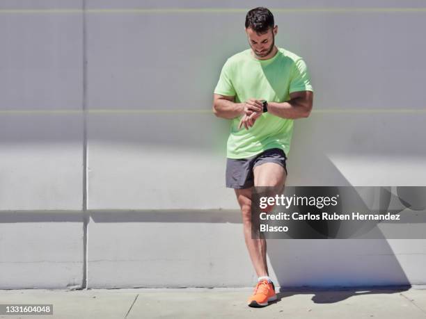 young man looking at the data on his smartwatch after doing sport - running gear stock pictures, royalty-free photos & images