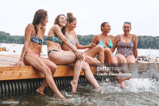 young adult women having fun on the beach and splashing water by the legs - legs in water fotografías e imágenes de stock