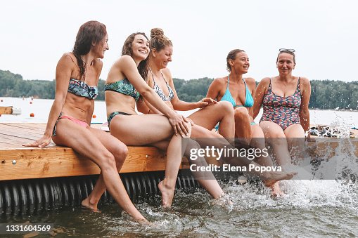 Young Adult Women Having Fun On The Beach and Splashing Water By The Legs