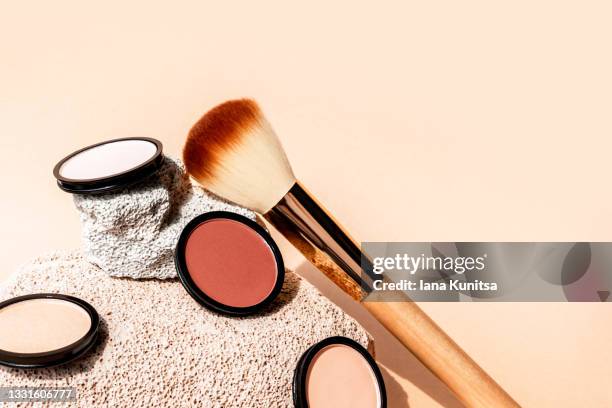 compact face powder, blush, eye shadow and blush brush on beige background with porous stones. space for text. cosmetics for contouring. - rouge stockfoto's en -beelden