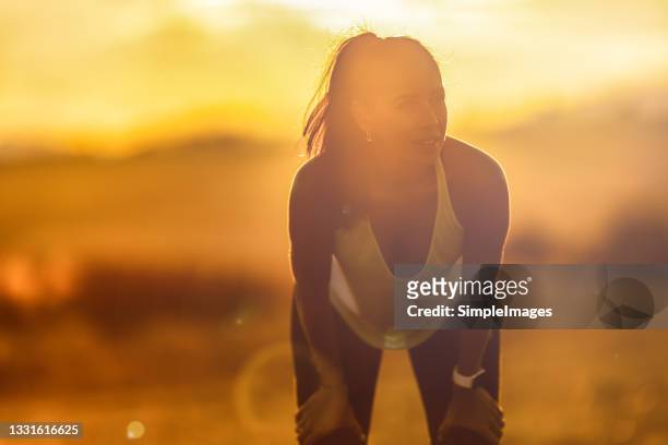 sporting woman relaxing after workout outdoors during a sunset or a sunrise. - hot summer nights film stock-fotos und bilder
