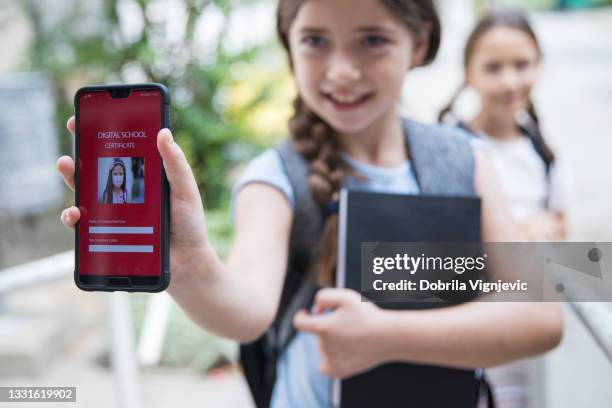 電話でデジタル学校の証明書を保持しているかわいい女子高生 - 子供のみ ストックフォトと画像