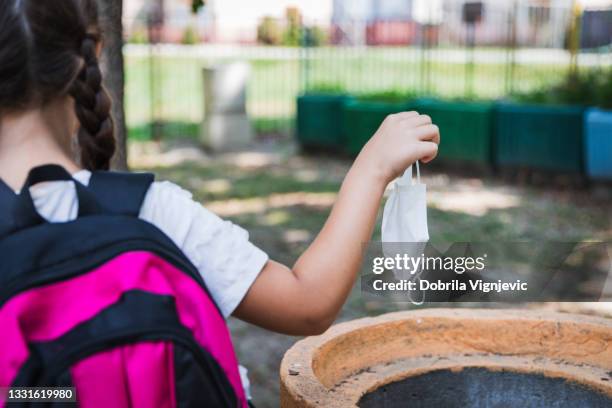 rear view of school girl throwing away protective mask - school life balance stock pictures, royalty-free photos & images