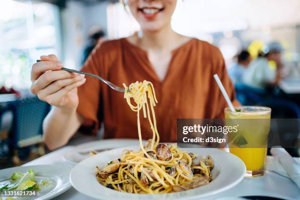 close up of young asian woman eating freshly served linguine pasta with fresh clams for lunch in a restaurant. eating out lifestyle - woman eat noodles imagens e fotografias de stock