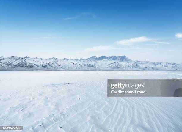 snowcapped mountain and flat snowfield - snow covered road stock-fotos und bilder