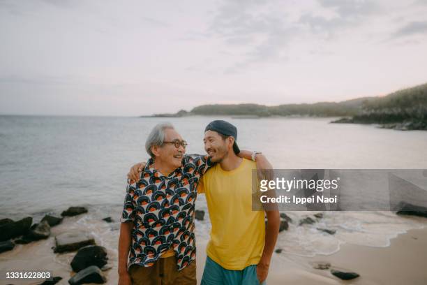 senior father and adult son having a good time on beach at dusk - coastal feature stock pictures, royalty-free photos & images