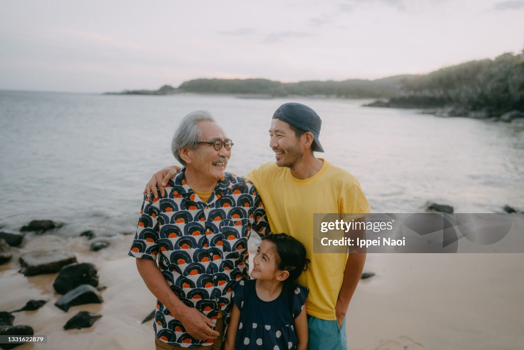 Three generation family having a good time on beach at dusk