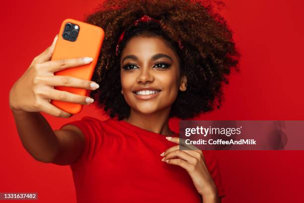 pretty young afro woman holding a smart phone - woman selfie stock pictures, royalty-free photos & images