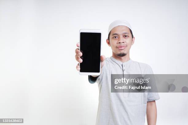 asian muslim young man showing smartphone with blank screen - hand showing stock-fotos und bilder