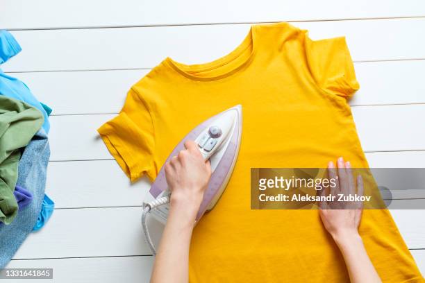 lots of bright dirty or clean colorful scattered clothes, abstract background. a woman or girl is ironing a t-shirt. the concept of homework and responsibilities, lack of time for household chores. - t shirt texture stock pictures, royalty-free photos & images