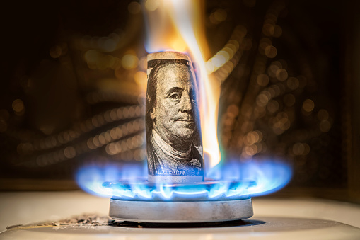 american dollar is burning in the fire. Burning gas burner on the background of one hundred dollars. The concept the rise in the price of gas in USA. Expensive gas supply