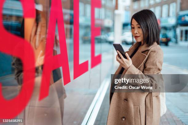 young woman window shopping on street in city - desire foto e immagini stock