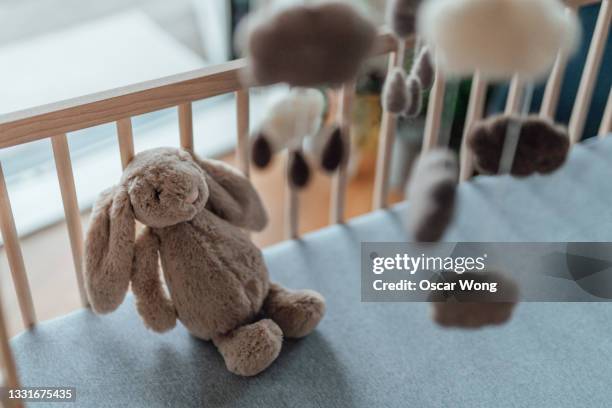 stylish scandinavian newborn baby nursery with natural wooden baby cot, stuffed bunny and handmade hanging mobile - baby mobile stock pictures, royalty-free photos & images