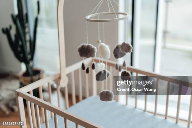 stylish scandinavian newborn baby nursery with natural wooden baby cot and handmade mobile hanging over it - productos para bebé fotografías e imágenes de stock