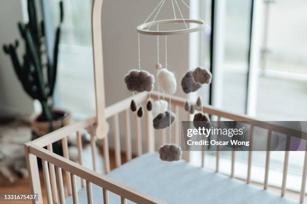 stylish scandinavian newborn baby nursery with natural wooden baby cot and handmade mobile hanging over it - nursery bedroom stock pictures, royalty-free photos & images