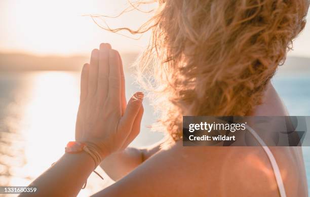 schöne frau meditiert, macht yoga, während hände in gebetsposition im salda-see - namaste stock-fotos und bilder