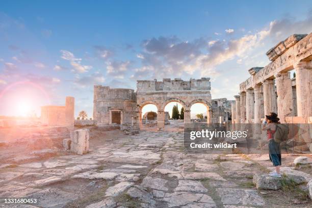 photographer tourist girl is taking photos of the frontinus gate in ancient ruins in hierapolis , pamukkale - pamukkale stock pictures, royalty-free photos & images