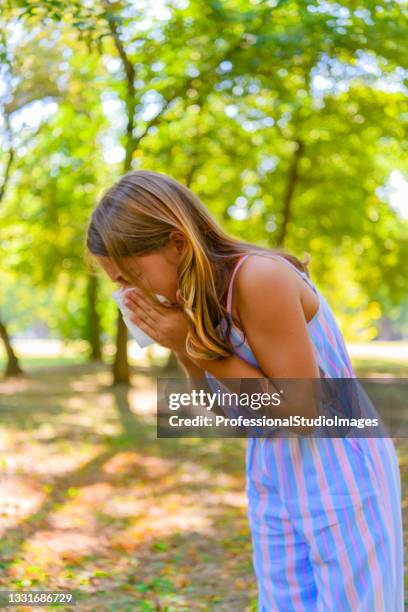 a girl with flu is walking in public park and sneezing in paper tissues. - snyta sig bildbanksfoton och bilder