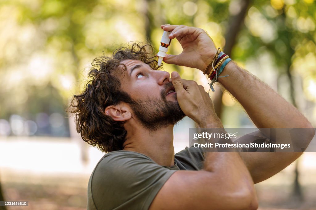 A Mature Man with Eye Problems is Applying Eye Drops in Nature.