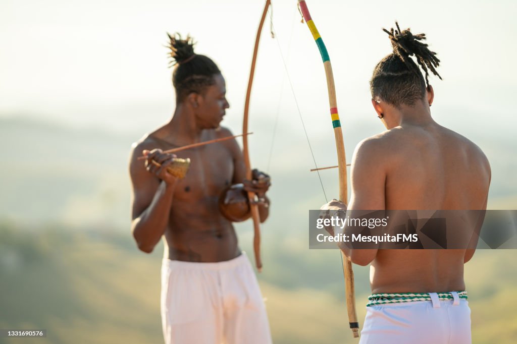 Capoeira men playing berimbau