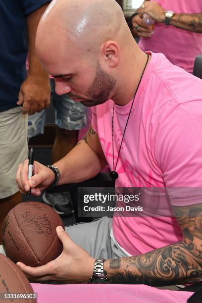 Mike Caussin signs a football during the CHARM Back to School Bash at Catholic Charities at C. E. McGruder on July 31, 2021 in Nashville, Tennessee.