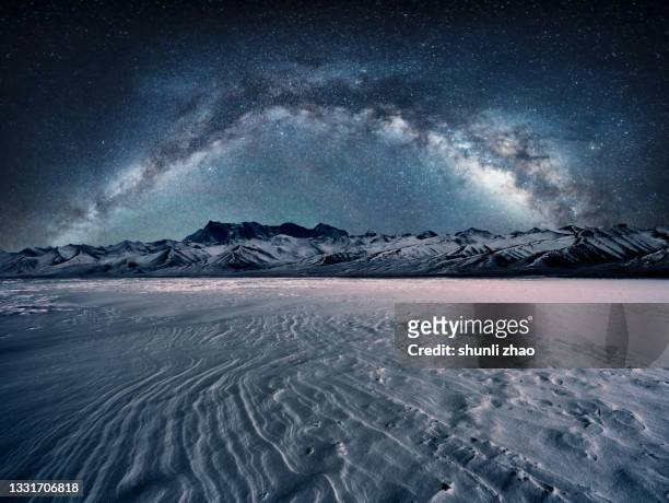 snowcapped mountain and flat snowfield under the galaxy arch bridge - winter road stock pictures, royalty-free photos & images
