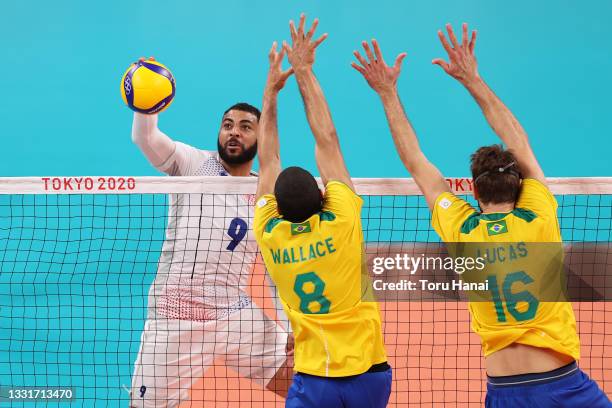 Earvin Ngapeth of Team France hits past Wallace de Souza of Team Brazil and Lucas Saatkamp during the Men's Preliminary Round - Pool B volleyball on...