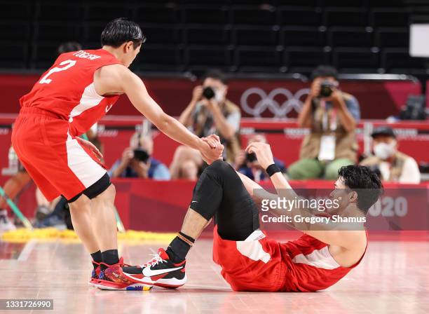 Yuki Togashi helps Yuta Watanabe of Team Japan up from the court during the first half of a Men's Basketball Preliminary Round Group C game against...