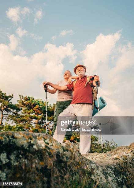 foto eines älteren paares während ihrer wanderung mit rucksäcken, erreicht den gipfel des berges - old couple adventure stock-fotos und bilder